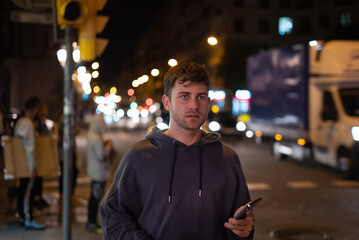 Man with smartphone on street at night