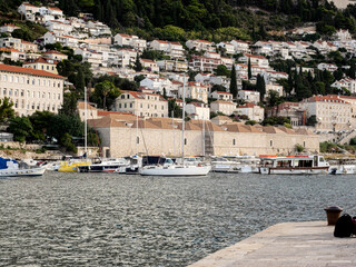 Hillside cityscape view of red roofed homes and boats surrounding Adriatic cove in Dubrovnik, Croatia.