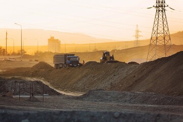Excavators work the construction on road site at sunset