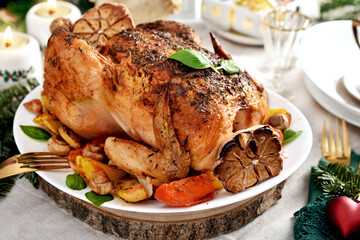 Roasted whole chicken with vegetables and garlic on Christmas table