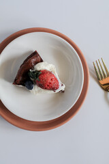 Delicious chocolate flourless cake with strawberry, blueberry and whipping cream on white background. Homemade bakery concept