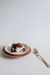 Delicious chocolate flourless cake with strawberry, blueberry and whipping cream on white background. Homemade bakery concept