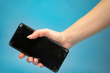 Woman holding smartphone with broken edges and screen