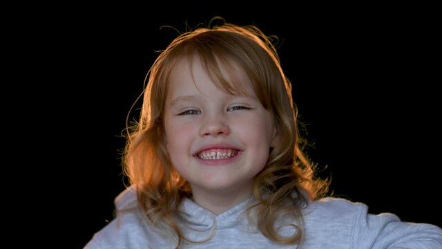 Close up portrait of cheerful little girl on dark studio background
