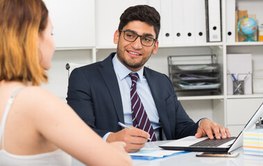 Positive businessman welcoming female client at workplace in office