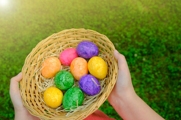 Easter Egg Hunt. Easter eggs set in a basket in children's hands on green grass background. Collecting eggs. Religious holiday tradition. Colorful easter eggs.Easter holiday symbol