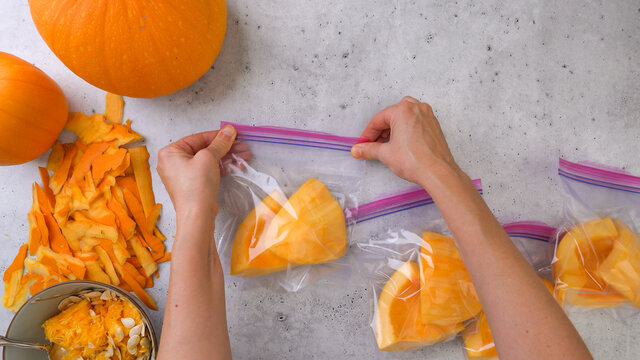 Fresh raw peeled pumpkin slices in zip lock bags close up, ready to be frozen.