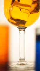 Closeup photo of drink in a glass with ice cubes on a bokeh blur background of colored drink glasses