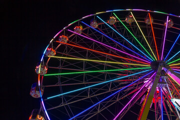 An illuminated wonder wheel at night with a black sky