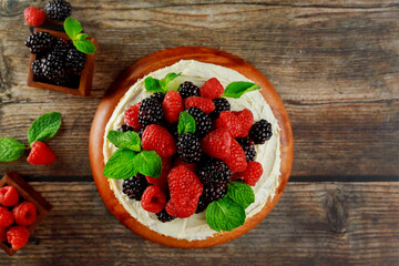 Top view of homemade berry cake decorated with fresh raspberries and blackberries.