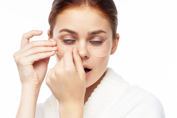 Woman in white robe posing fun skin care patches on face