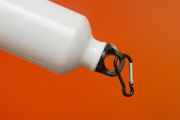 white aluminum bottle with black plastic stopper on orange background