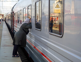 Departure of the train. Farewell of a woman in a headscarf at the station.