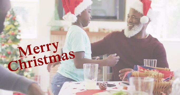 Merry christmas text banner against african american boy hugging his grandfather at home