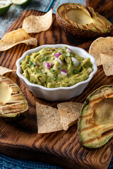 Close up of a bowl of homemade guacamole surrounded by tortilla chips. 
