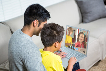 Obraz premium Biracial boy with father using laptop for video call, with elementary school pupils on screen