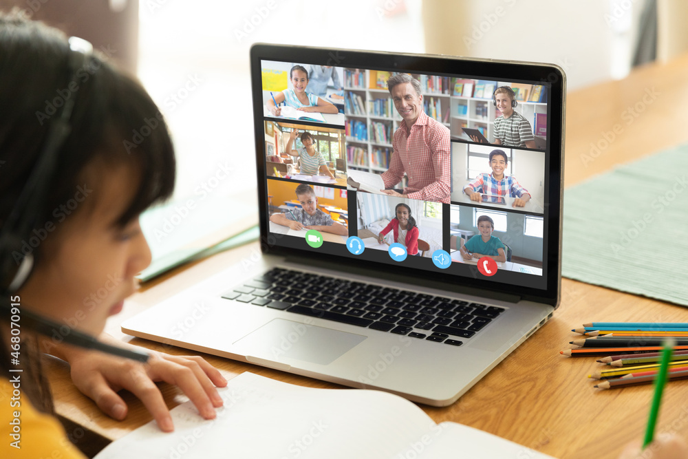 Wall mural Asian girl using laptop for video call, with smiling diverse elementary school pupils on screen