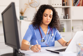 Portrait of female doctor working on laptop computer consulting patient online, telemedicine concept
