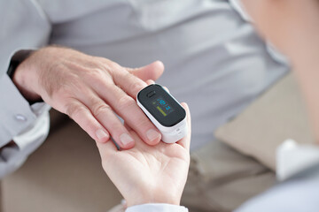 Doctor checking if oxygen saturation of senior patient recovered from coronavirus is okay