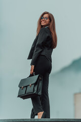 A business woman in a suit with a briefcase in her hand goes to work. Selective focus. Business...