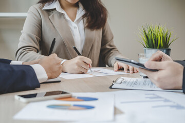 Business meeting, asian group man, woman brainstorm analyzing graph data of cost plan, discussing in board room, using touchpad or laptop computer on table or desk. People working conference room.