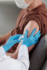 Doctor in protective gloves vaccinating patient against coronavirus