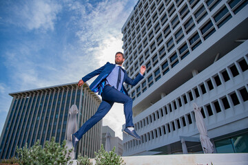 Businessman running, hurrying to work. Full length of young business man while jumping along the street.