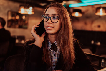 An attractive business woman using a smartphone while sitting in a modern cafe. Business portrait. Selective Focus.