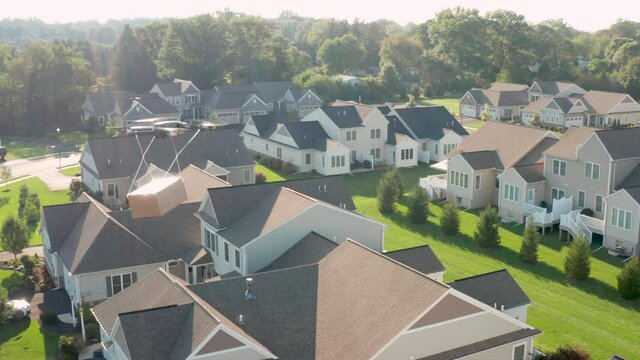Futuristic drone package delivery to homes. Aerial of box in midair flight over houses in USA neighborhood.