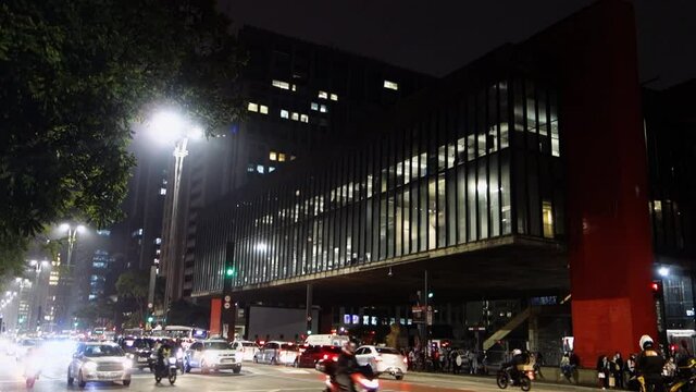 vehicular traffic on busy Paulista avenue, at night. Art museum of Sao Paulo on background
