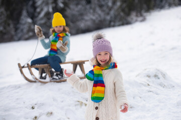 Child girl enjoying snow ball play outdoors. Kids sled in the Alps mountains in winter. Outdoor fun for family christmas vacation.