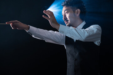 The image of a maestro wielding a conductor's rod at a concert. He looks Asian and South American.