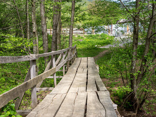 Fototapeta premium Wooden bridge, in summer in a mountain chalet, crossing a small river in retro style.