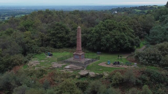 Aerial view sandstone obelisk war memorial Frodsham hill overlooking Cheshire Liverpool skyline left orbit shot