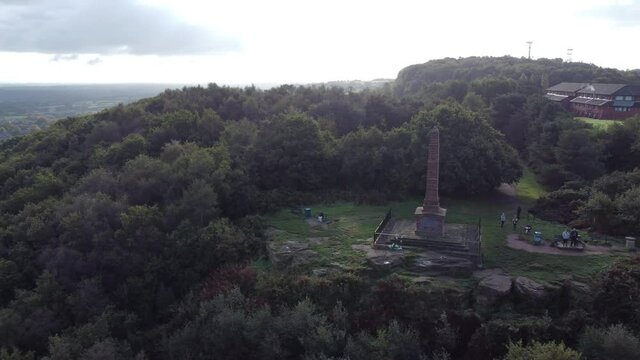 Aerial view sandstone obelisk war memorial Frodsham hill overlooking Cheshire Liverpool skyline pan right