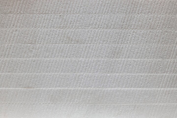 White wide sheets of expanded polystyrene in a stack, texture. Side view. Construction industry.