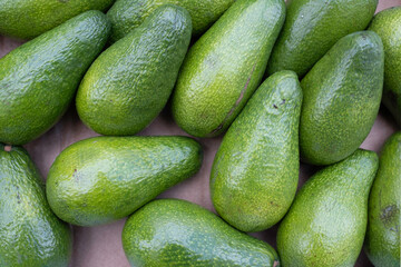 A number of shiny green avocados are displayed in a greengrocer's shop