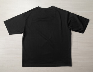 Blank Black Oversized T-shirt mockup template on the floor.