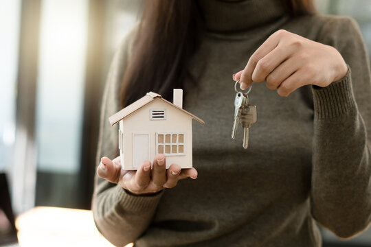 Real Estate Broker Or businessman holding white house model and house key in hand.Mortgage loan approval home loan and insurance concept. - Powered by Adobe