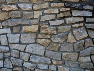 Obraz premium beautiful stone texture with rough cobblestone protrusions and deep border lines, stone pattern in the structure of the exterior design of a fence or facade, an element of architecture using natural s