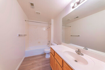Plain white windowless bathroom with wooden vanity sink and wall mirror