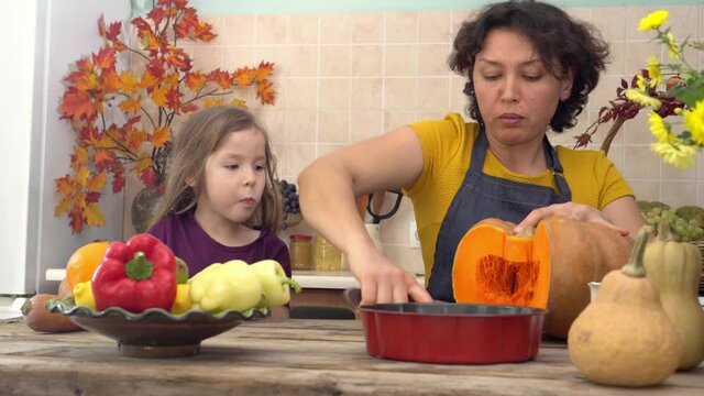 Mother and daughter cook pumpkin meals at home. Cooking together for a festive Thanksgiving dinner. A farmer's family celebrates the harvest festival