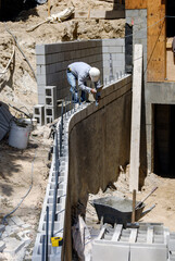 Block mason working on a large retaining wall