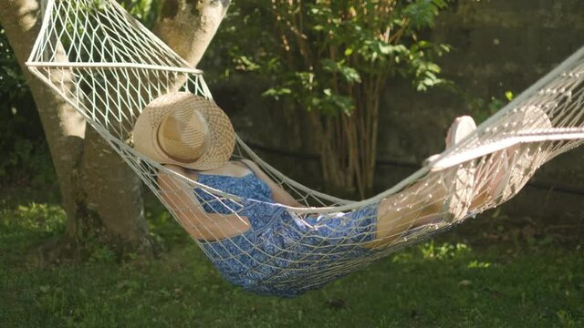 woman taking a nap in a hammock under the shade of the tree. Slowmotion