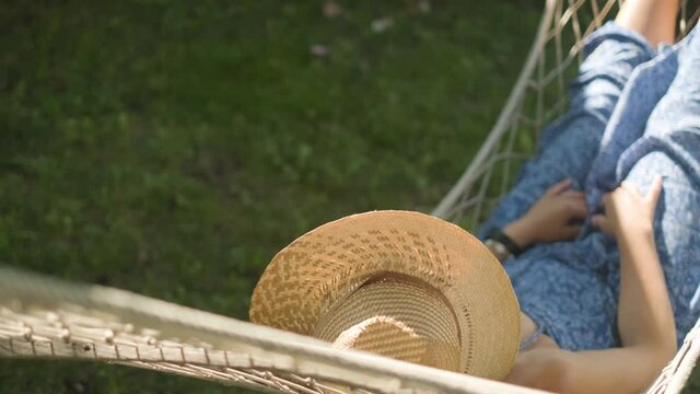 woman wearing a straw hat swings in a hammock. Slowmotion