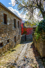 Traditional architecture  with  a narrow road and stone buildings  during  fall season in the picturesque village of papigo , zagori Greece