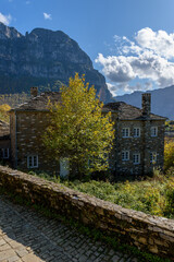 Fototapeta na wymiar view of traditional architecture with stone buildings and background astraka mountain during fall season in the picturesque village of papigo , zagori Greece