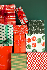 Christmas inspiration. A lot of wrapped beautiful gifts lie against the background of a green wall. Composition of holiday gifts for a large family at home. Christmas mood.