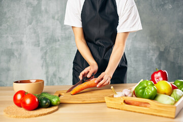 Cook woman on the kitchen cutting vegetables cutting board