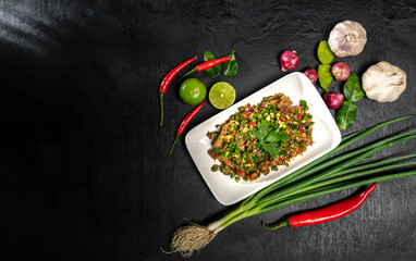 Pork belly mixing in salt and chili with many herbs. A delicious recipe from Asia and spices ingredients on black wooden table background copy space, Thai food, Asian foods, Thailand restaurant menu